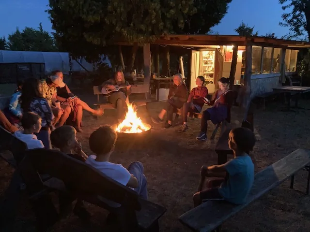 Gruppe musiziert abends um ein Lagerfeuer