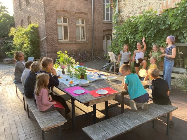 Gruppe sitzt zusammen an einem gestalteten Tisch im Pfarrhof